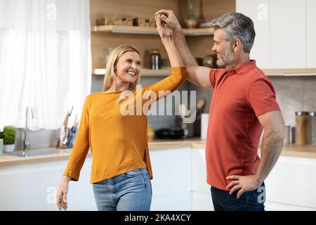 Schöne Ehegatten mittleren Alters tanzen zusammen in der Küche Stockfoto