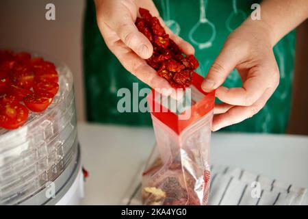 Frau in ihrer Küche bereitet sonnengetrocknete Tomaten zu Stockfoto