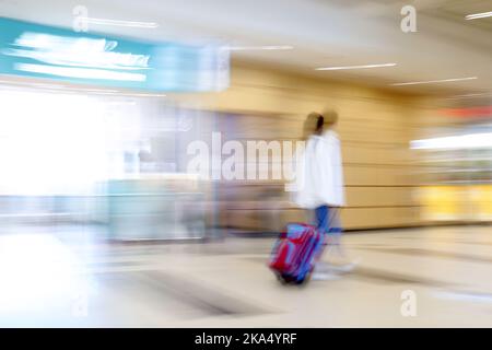 Eine verschwommene Reisende Frau mit einem Koffer Stockfoto