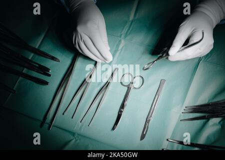 Die Hand des Arztes nimmt ein chirurgisches Instrument vom Tisch Stockfoto
