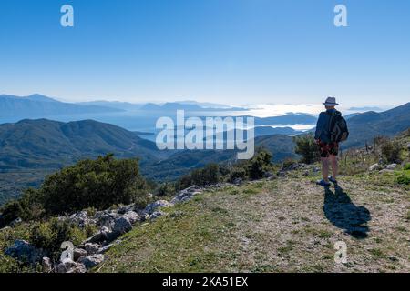 Ein Tourist, der bei einem Wanderurlaub den Panoramablick von einem Berggipfel genießt. Stockfoto