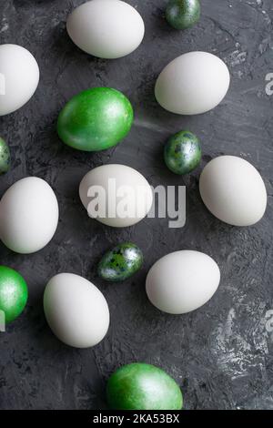 Weiße Eier mit Grün auf grauem Hintergrund, Draufsicht, flach liegend, Nahaufnahme. Osterhintergrund. Stockfoto