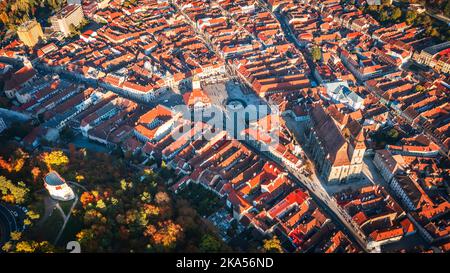 Brasov, Rumänien - Luftdrohnenansicht der historischen Innenstadt, des Rathausplatzes, des Withiten-Turms und der Schwarzen Kirche, herbstliche Landschaft in Siebenbürgen. Stockfoto