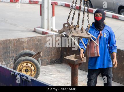 SAMUT PRAKAN, THAILAND, SEP 16 2022, Ein Arbeiter manipuliert Ketten, die an einem Kranhaken hängen Stockfoto