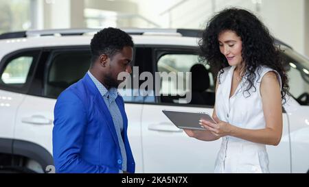 Kundin unterzeichnet Vertrag über den Verkauf von Elektroautos auf einem Tablet Stockfoto