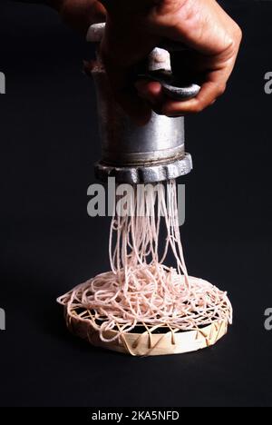 Homebrüh-Trichter. Dame macht Trichter mit traditionellen Geräten und Mehl. Lady Hände und Ausrüstung auf schwarzem Hintergrund sri lanka. Stockfoto