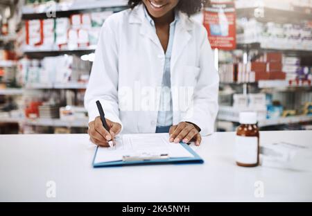 Ich habe etwas für Sie, das alle Anforderungen erfüllt: Eine nicht erkennbare junge Apothekerin, die in einer Apotheke arbeitet. Stockfoto