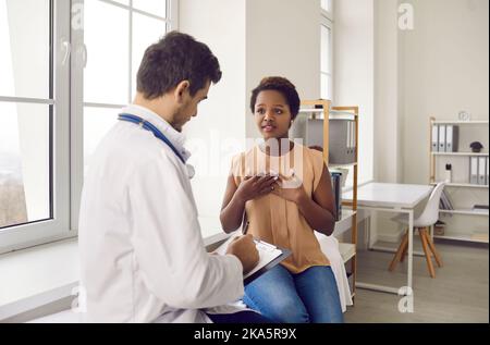 Eine junge Frau beschwert sich bei der medizinischen Untersuchung über Brustschmerzen und Atembeschwerden. Stockfoto