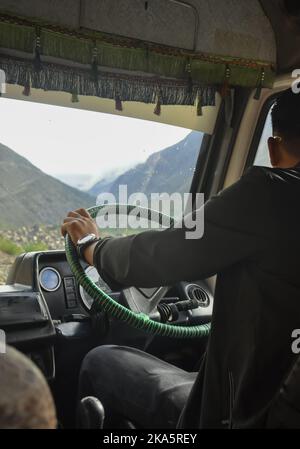 Rückansicht eines unbekannten Mannes, der während der Sommersaison auf der Manali-Leh-Autobahn einen Kleinbus fährt Stockfoto