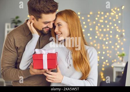 Junge Frau hält Box mit Valentinstag Geschenk und danken ihrem Freund für das Geschenk Stockfoto