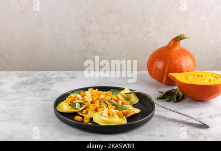 Saisonales Herbstrezept. Kürbisravioli mit Salbei, Parmesan und Olivenöl. Stockfoto