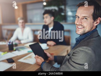 Ich trete nie ohne sie in ein Meeting ein. Porträt eines reifen Geschäftsmannes, der ein digitales Tablet verwendet, während er in einem Büro in einer Besprechung ist. Stockfoto