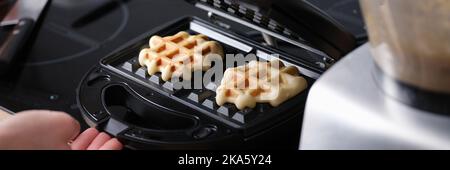 Waffeln in Waffeleisen in Nahaufnahme zu Hause kochen Stockfoto