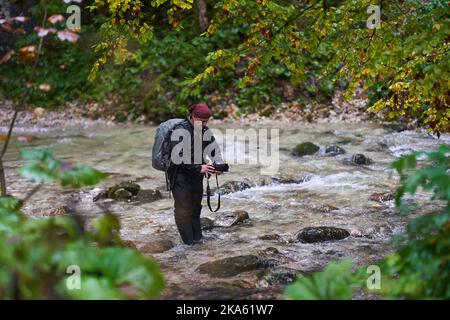Professioneller Naturfotograf, der an einem regnerischen Morgen Landschaften in einer Schlucht mit einem Fluss fotografiert Stockfoto