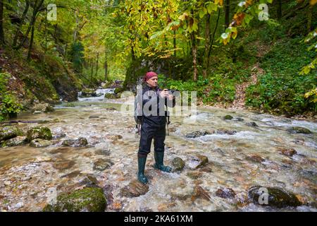 Professioneller Naturfotograf, der an einem regnerischen Morgen Landschaften in einer Schlucht mit einem Fluss fotografiert Stockfoto