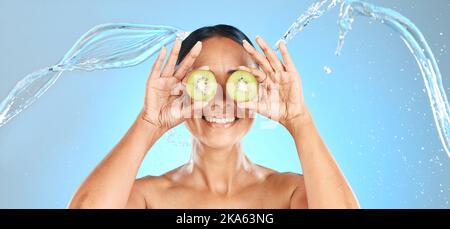 Kiwi Obst, Frau und Beauty Wasser Spritzer für Naturkosmetik, Gesichtsmaske und gesunde Hautpflege Produkt auf Studio blauen Hintergrund. Fröhliches Model-Gesicht Stockfoto