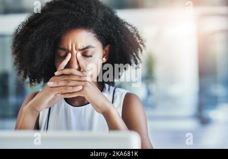 Diese Kopfschmerzen werden immer ablenkender. Eine attraktive junge Geschäftsfrau, die in ihrem Büro Kopfschmerzen hat. Stockfoto