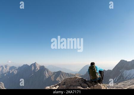 Mann auf der Spitze des Berges mit Rucksack genießen Sie die Aussicht. Stockfoto