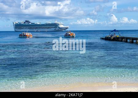 Passagiere, die durch kleine Ausschreibungen des vor Kiriwina Island, Papua-Neuguinea verankerten Kreuzfahrtschiffes an den Anlegesteg gebracht werden Stockfoto