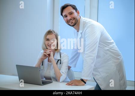 Zwei Menschen in Laborkittel diskutieren etwas und schauen interessiert Stockfoto