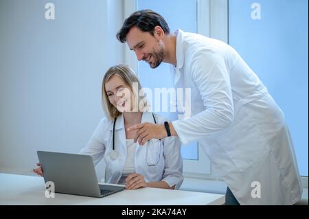 Zwei Menschen in Laborkittel diskutieren etwas und schauen interessiert Stockfoto