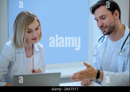 Zwei Ärzte sitzen dicht und diskutieren etwas Stockfoto