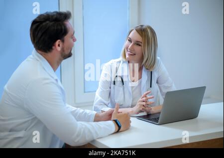 Zwei Menschen in Laborkittel diskutieren etwas und schauen interessiert Stockfoto