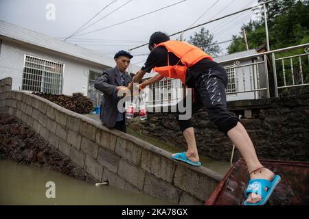 (200707) -- SHIMEN, 7. Juli 2020 (Xinhua) -- Ein Retter (R) bringt Trinkwasser zu einem Dorfbewohner, der von einer Überschwemmung in der Gemeinde Yanchi im Bezirk Shimen, der Provinz Hunan in Zentralchina, gefangen ist, 7. Juli 2020. In den letzten Tagen kam es zu einer von Regen ausgelösten Überschwemmung in der Grafschaft. (Xinhua/Chen Sihan) Stockfoto