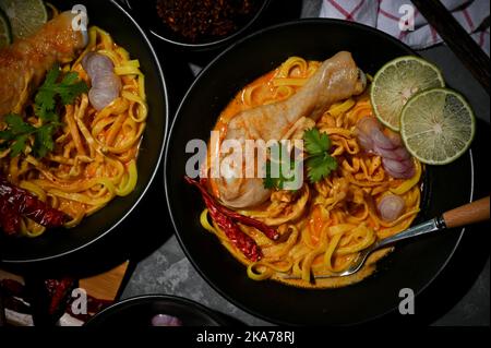 Traditionelle nordthailändische Küche, Khao Soi Kai, würzige cremige Kurrnudeln mit Hähnchendrumstick und Eiernudeln. Draufsicht Stockfoto