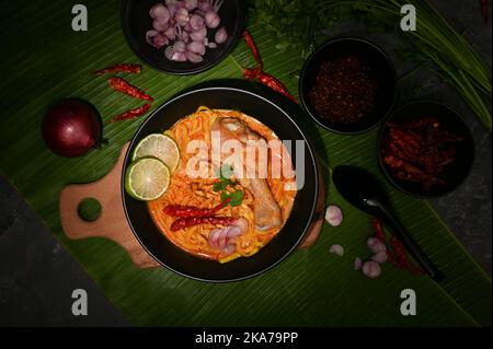 Blick von oben, Khao Soi Kai oder einzigartiges nordthailändisches würziges Kerri mit Eiernudeln, Huhn und Gemüse. Stockfoto