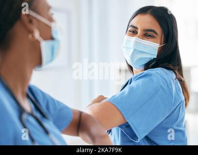 Covid, Frauen und Ärzte begrüßen den Ellenbogen in einer chirurgischen Maske im Krankenhaus oder in der Klinik während der Pandemie. Teamarbeit, Mitarbeiter im Gesundheitswesen und Medizin Stockfoto