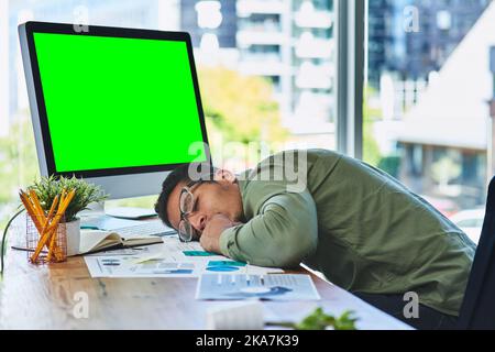 Er arbeitet hart und schläft auch hart. Ein müder junger Geschäftsmann schläft tagsüber auf seinem Schreibtisch im Büro. Stockfoto