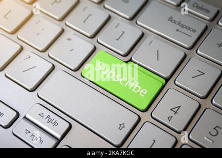 Grüne Abonniere-Taste auf der Laptop-Tastatur in Nahaufnahme. Stockfoto