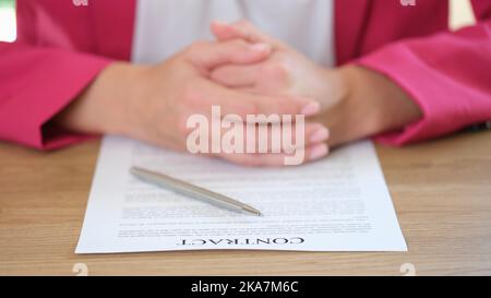 Geschäftsfrau, die einen Vertrag und einen silbernen Stift in die Hand legt Stockfoto