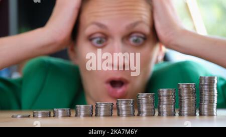 Frau, die auf Haufen von Münzen schaut und am Kopf hält Stockfoto