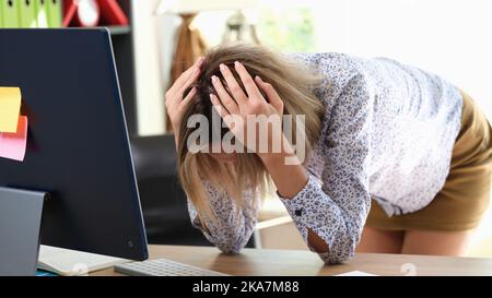 Gestresste Frau, die den Kopf mit den Händen im Büro hält Stockfoto