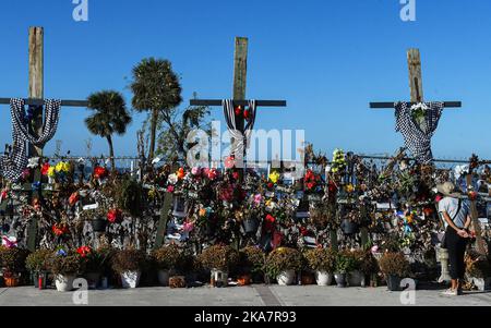 Fort Myers, Usa. 31. Oktober 2022. Eine Frau blickt im Centennial Park in Fort Myers, Florida, auf ein provisorisch anhaltendes Mahnmal mit Blumen, Kreuzen und Fotos für die Opfer des US-Unfallheers Ian. Der Sturm verursachte schätzungsweise $67 Milliarden versicherte Schäden und mindestens 127 stürmbedingte Todesfälle in Florida. Kredit: SOPA Images Limited/Alamy Live Nachrichten Stockfoto