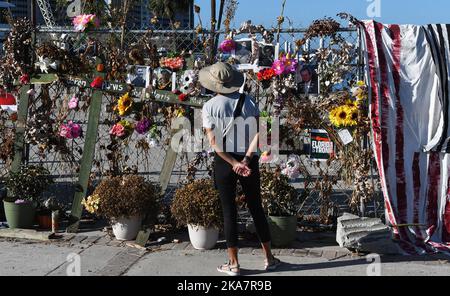 Fort Myers, Usa. 31. Oktober 2022. Eine Frau blickt im Centennial Park in Fort Myers, Florida, auf ein provisorisch anhaltendes Mahnmal mit Blumen, Kreuzen und Fotos für die Opfer des US-Unfallheers Ian. Der Sturm verursachte schätzungsweise $67 Milliarden versicherte Schäden und mindestens 127 stürmbedingte Todesfälle in Florida. Kredit: SOPA Images Limited/Alamy Live Nachrichten Stockfoto