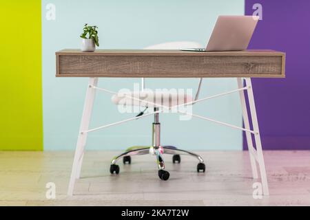 Moderne Möbel vor einem farbenfrohen Hintergrund mit einem Laptop Stockfoto