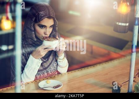 Ruhige Momente beim Kaffee. Eine junge Frau, die eine Tasse Kaffee in einem Café trinkt. Stockfoto