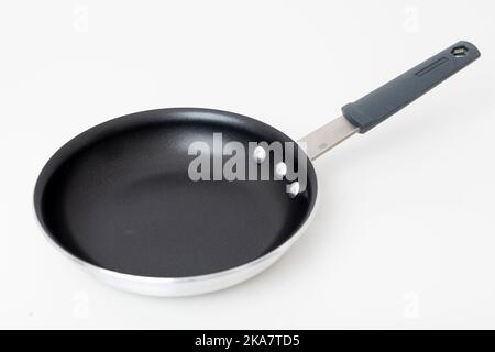 Eine antihaftbeschichtete Bratpfanne aus Edelstahl, die auf einen schlichten weißen Hintergrund geschossen wurde. Stockfoto