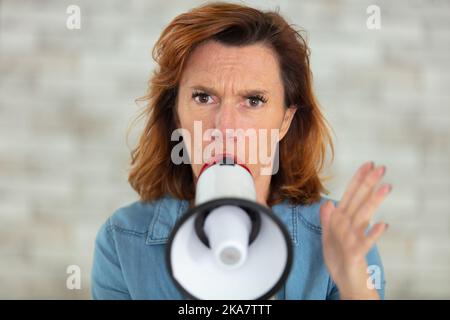 Frau im mittleren Alter spricht mit einem Megaphon Stockfoto