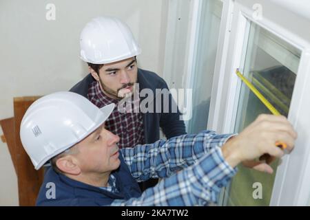 Bauarbeiter installieren neue Fenster im Haus Stockfoto