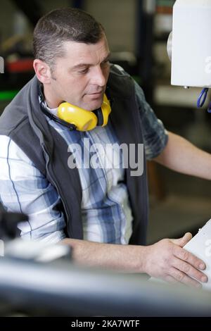 Mann, der eine Maschine in einer Fabrik betreibt Stockfoto