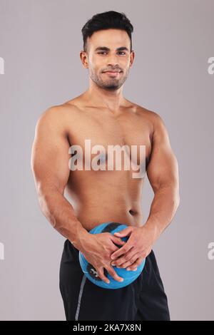 Fitness, Portrait und Mann mit Medizinball für Sport, Training und Bewegung vor grauem Studiohintergrund. Wellness, Training und Portrait eines Stockfoto