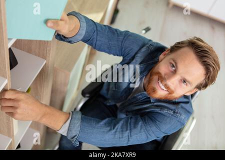 Gealterter Mitarbeiter im Rollstuhl, der im Büro arbeitet Stockfoto