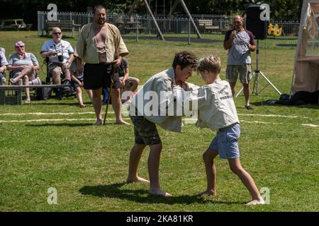 Ein Richterschiedsrichter Stickler beobachtet zwei junge Jungen, die beim Grand Cornish Wrestling Tournament auf dem malerischen Dorfgrün von St. Mawgan in antreten Stockfoto