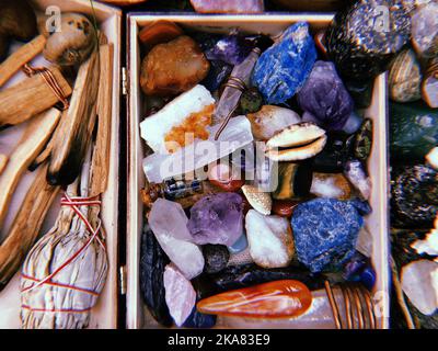 Ein Blick von oben auf Palo Santo Sticks und bunte Kristall Heilsteine in einer Box für Meditation Stockfoto