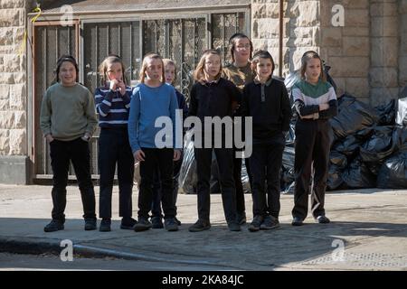 Während der Yeshiva-Pause starren 8 orthodoxe jüdische Jungen, jeder mit langem Peyot, auf etwas auf der anderen Straßenseite. In Brooklyn, New York City. Stockfoto