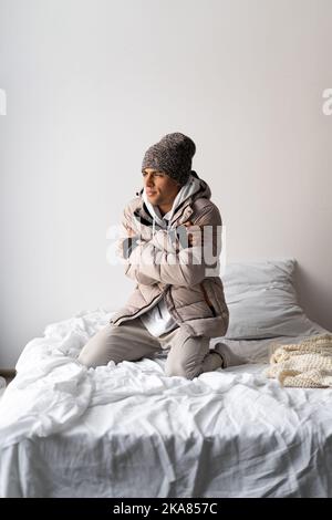 Erneuerbare Energiequellen. Energiekrise. Ein Bürger friert im Schlafzimmer ein. Erhöhung des Erdgaspreises für die Heizenergie. Haben Sie ein Problem mit Stockfoto